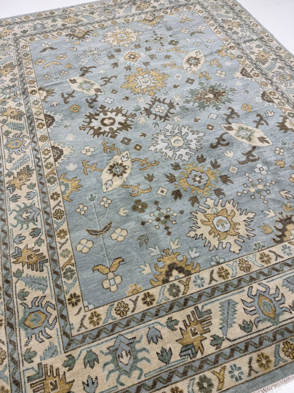 Katherine hand-knotted wool modern Oushak rug in light blue with cream, tan, ochre, and green