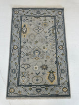 Margot modern Oushak rug, hand-knotted wool with a gray center, light blue border, and mustard, green, cream, and navy accents