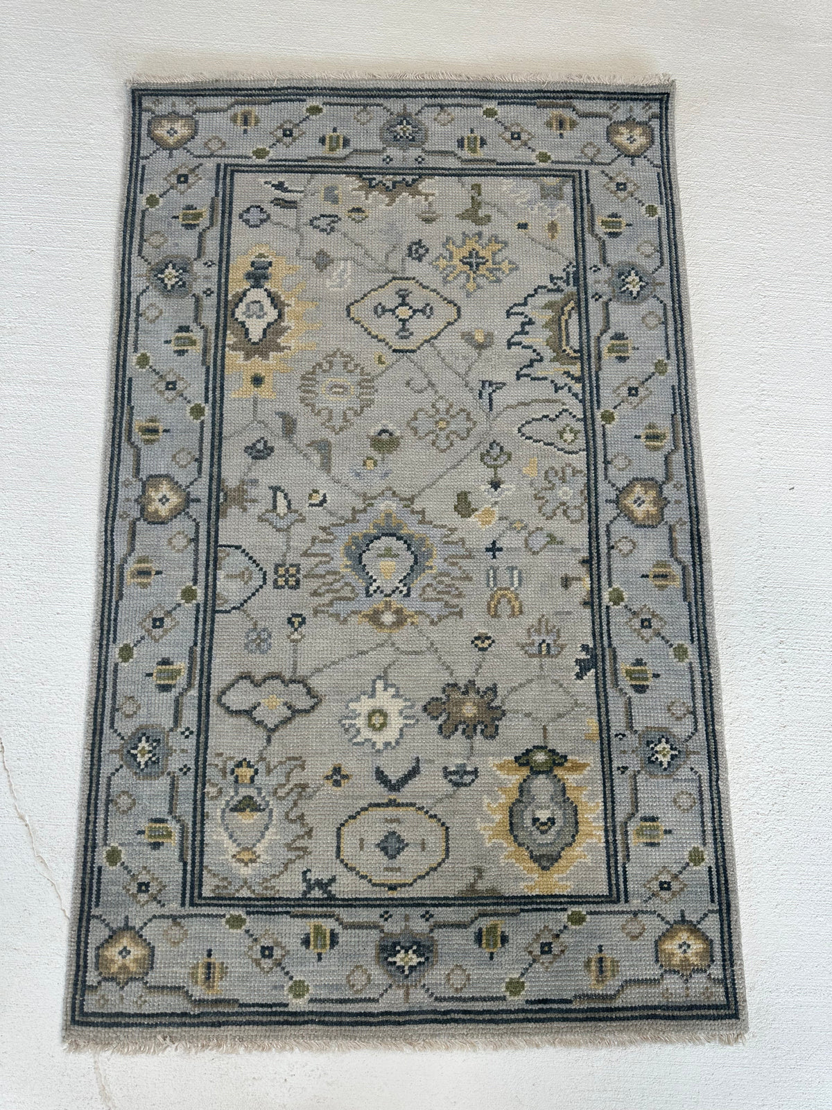 Margot modern Oushak rug, hand-knotted wool with a gray center, light blue border, and mustard, green, cream, and navy accents